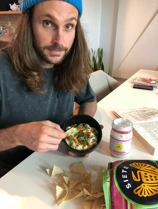 Noah, Coconut Cult founder, in a blue beanie showing a Thanksgiving appetizer with probiotic guacamole and yogurt.