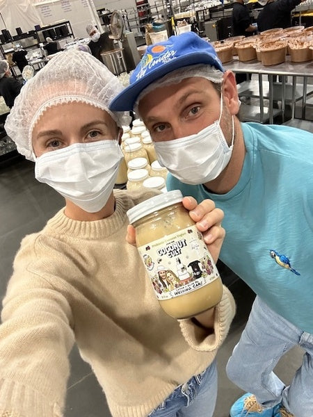 Noah & Brittany at the Coconut Cult Factory holding a jar of Coconut Cult yogurt